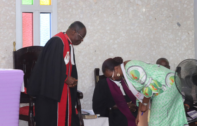 L'évêque de Côte d'Ivoire Benjamin Boni et Lydie Acquah, directrice de la radio La Voix de l'Espérance, se saluent tout en évitant de se serrer la main lors du culte de clôture de la célébration des 10 ans de la radio, le 15 mars. L'Eglise insiste sur les mesures visant à freiner la propagation de COVID-19. Photo de Isaac Broune, UM News.