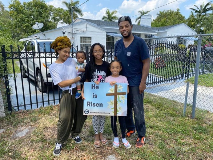 A family from First United Methodist Church of Miami stands with a yard sign given to them by the church. Photo by Kipp Nelson, First United Methodist Church of Miami.