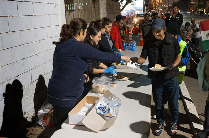Volunteers from the Methodist Church of Mexico feed people outside a makeshift camp for migrants at the Benito Juarez sports complex in Tijuana, Mexico, in December 2018. The program was forced to close April 3 due to the coronavirus. File photo by Mike DuBose, UM News.