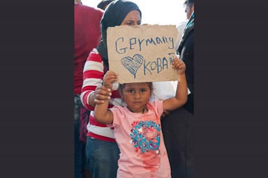 A young migrant girl hoping to reach Germany with her family holds up a sign inside the Hungarian border.  Photo by Oláh Gergely Máté. A young migrant girl hoping to reach Germany with her family holds up a sign inside the Hungarian border.  Photo by Oláh Gergely Máté.