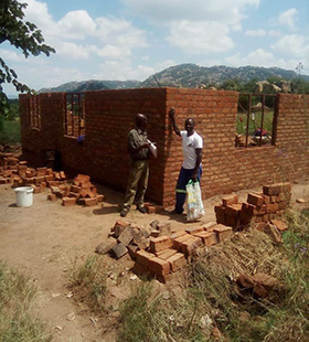 L'ingénieur Cassian Mutsambiwa et le bâtisseur Pamganai Ziwewe se tiennent devant la nouvelle maison de quatre chambres que l'Église Méthodiste Unie construit pour Elizabeth Hwatira et sa famille à Bikita, Masvingo. La maison de cette famille a été détruite par le cyclone Idai en 2019. Photo de Chenayi Kumuterera, UM News.