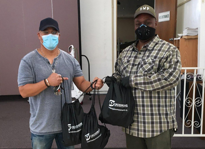 Saun Hough (left), associate pastor at Crossroads United Methodist Church in Compton, Calif.,  hands reentry hygiene kits to Jerrel McCoy, lead community health worker at SHIELDS For Families. The church mobilized to create 3,500 kits for citizens released from prison by the state of California. Photo courtesy of Crossroads United Methodist Church.