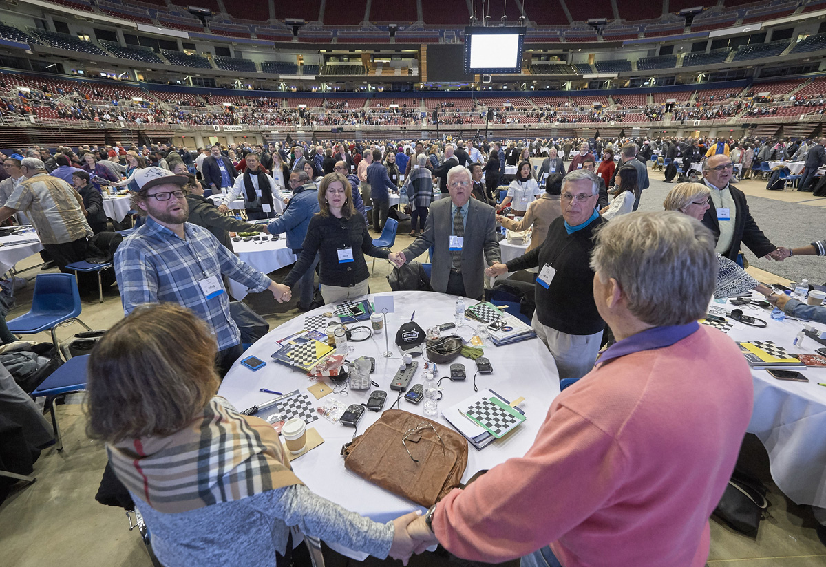 Os delegados dão as mãos e oram em 23 de fevereiro de 2019, no plenário de abertura da sessão extraordinária da Conferência Geral realizada em St. Louis. Foto de arquivo de Paul Jeffrey, Notícias MU.