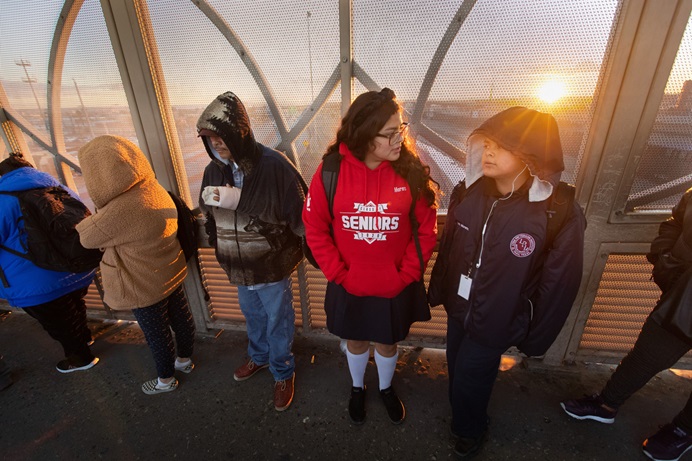 Ruth Moreno (in red sweatshirt) and her brother, Lino, make their way to school as the sun rises behind them on the Santa Fe Bridge over the Rio Grande in Juárez, Mexico, in November 2019. They made the two-hour cross-border journey each school day to attend the United Methodist Lydia Patterson Institute in El Paso, Texas, before in-person classes were halted due to the COVID-19 pandemic. File photo by Mike DuBose, UM News.