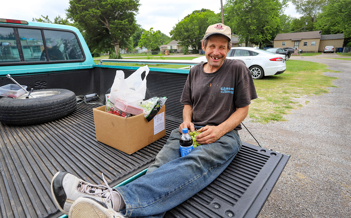 Michael, a food pantry participant, holds fresh grapes and other produce provided by Tulsa Indian United Methodist Church. He said he rarely has access to fresh fruit. Photo by Ginny Underwood, UM News.  