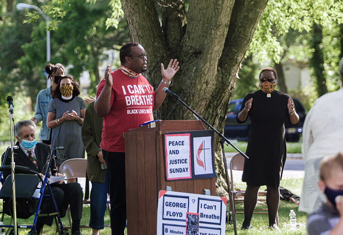 Lan Wilson (center), director of worship for the Greater New Jersey Conference, addresses those gathered during a Black Lives Matter rally June 7 in Willingboro, New Jersey. Seated behind Wilson is the Rev. Gilbert Caldwell, who also spoke. The Rev. Tanya Bennett, chairperson of GNJ’s Board of Church and Society (behind Wilson in striped dress) and the Rev. Vanessa Wilson, chairperson of GNJ’s Commission on Race and Religion (far right in black dress), listen. Photo by Aaron Wilson Watson.