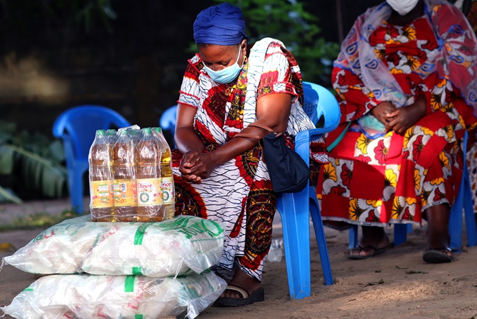 Akou Logbo a la tête baissée pendant que l’Evêque Benjamin Boni prie pour les victimes des inondations à Abidjan, en Côte d'Ivoire, et de la pandémie de la COVID-19. Elle fait partie des 300 veuves dont les activités ont été impactées par l’isolement lié à la COVID-19. Elles ont reçu des dons en vivres et non-vivres d’une valeur de 30 000 dollars, financés par UMCOR, l’agence d’assistance humanitaire de l’Eglise. Photo de Isaac Broune, UM News.