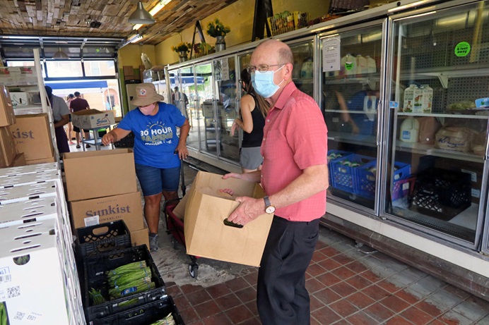 The Rev. John Edgar, executive director of Community Development for All People in Columbus, Ohio, adds a gallon of milk to a food box packed for one of the hundreds of customers who get food each day from the organization. Photo courtesy of Community Development for All People.