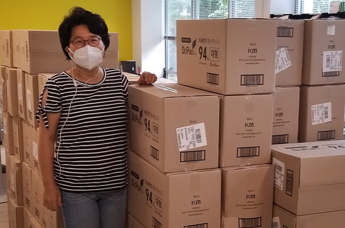 Grace Choi, current Global Ministries missionary in residence and a Yonsei alumnus, stands by a pile of donated masks. Choi worked at Yonsei Severance Hospital before she became a missionary. Photo courtesy of Grace Choi, Global Ministries.