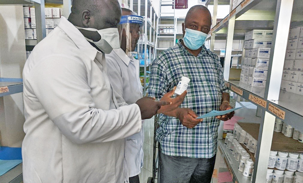 Allen S.D. Zomonway (right), a registered nurse and Ganta United Methodist Hospital administrator, reviews drug stocks with staff in the hospital pharmacy. During the pandemic, the Africa University graduate ensures that all hospital employees wear masks and take other necessary precautions. Photo courtesy of Africa University.