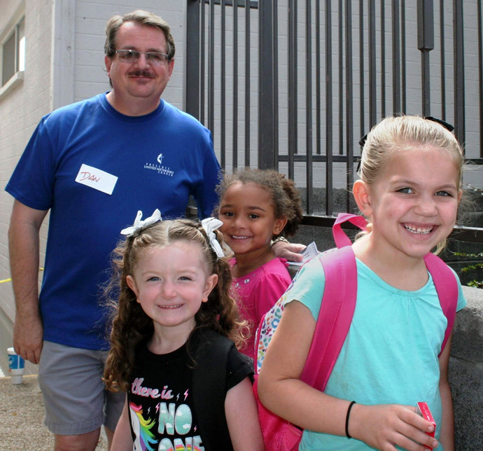 The Rev. Dan Hurlbert in this photo from before COVID-19 stands with children who have received backpacks from Prescott United Methodist Church in Arizona. This year, the church is giving away laptops to families who will return to school using only remote learning. Photo courtesy of the Rev. Hurlbert.