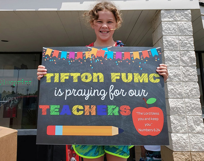 Katherine Paulk holds up a sign from Tifton First United Methodist Church in south Georgia that announces the church is praying for teachers. United Methodist congregations across the United States are finding ways to help schools address the challenges presented by COVID-19. Photo courtesy of Allison Lindsey, South Georgia Conference.