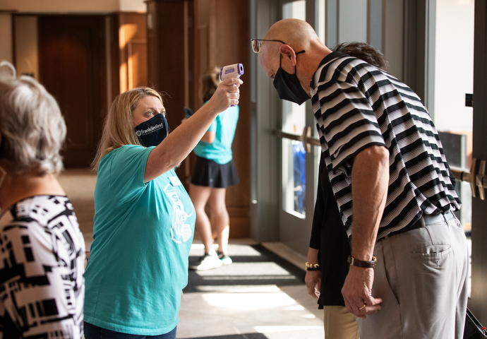 Volunteer Jennifer Jannetty checks James Crigger’s temperature as he arrives for worship at Franklin First United Methodist Church. Photo by Mike DuBose, UM News.