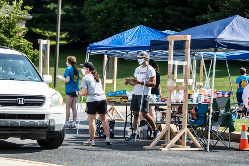 Los/as voluntarios/as hablan con las familias durante el día de entrega de morrales de la iglesia Wesley en Bethlehem, realizado el sábado. Foto de April Gamiz, The Morning Call.