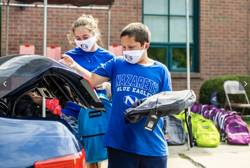 Los/as voluntarios/as Shannon Stivala de 13 años, a la izquierda y Ryan Golinsky, de 11 años cargan morrales de manera segura en el maletero de un automóvil durante el día de entrega de morrales de la iglesia Wesley en Bethlehem, realizado el sábado. Foto de April Gamiz, The Morning Call.