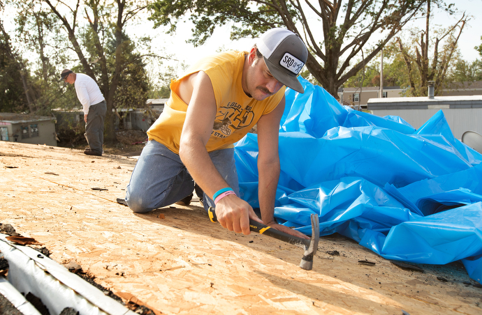 Jesse Parcher flattens roofing nails so they won’t tear a plastic tarp while he makes emergency repairs to a storm-damaged home in Marion, Iowa. Parcher was part of a volunteer team working with Marion First United Methodist Church. Photo by Mike DuBose, UM News.