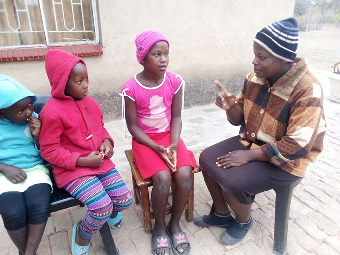 Perpetual Makadzange talks to her three children, (from left) 6-year-old Tizzy, 7-year-old Tanatswa and 12-year-old Tsepang, at their home in the Chimanimani, Zimbabwe. The United Methodist schools that the children attend remain closed to stop the spread of the coronavirus. Photo by Kudzai Chingwe, UM News. 
