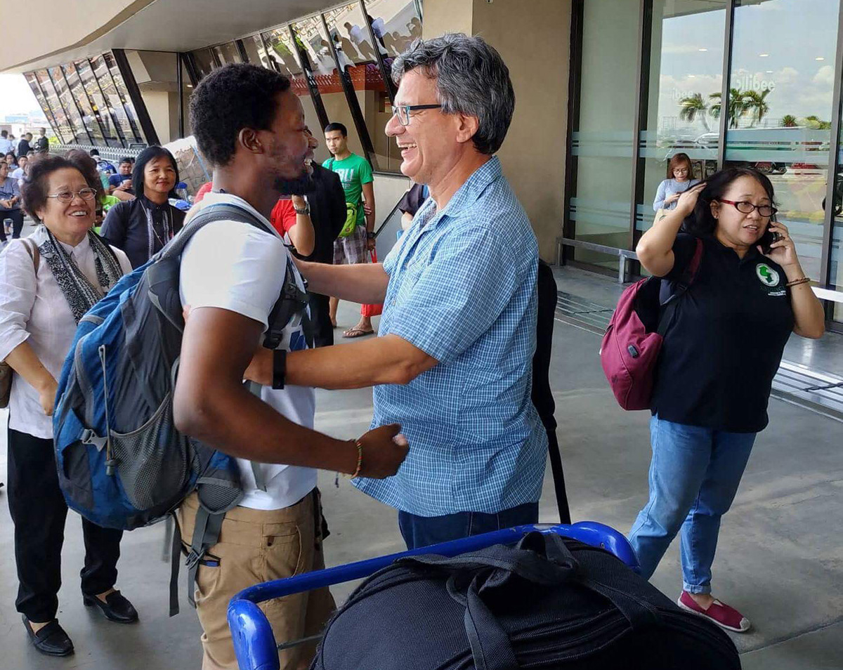 United Methodist missionary Tawanda Chandiwana (left foreground) is embraced by Thomas Kemper, head of the Board of Global Ministries, at the Ninoy Aquino International Airport in Manila, Philippines, on July 1, 2018, after Chandiwana was released from a detention center and allowed to leave the country. 2018 file photo courtesy of Thomas Kemper, Global Ministries.