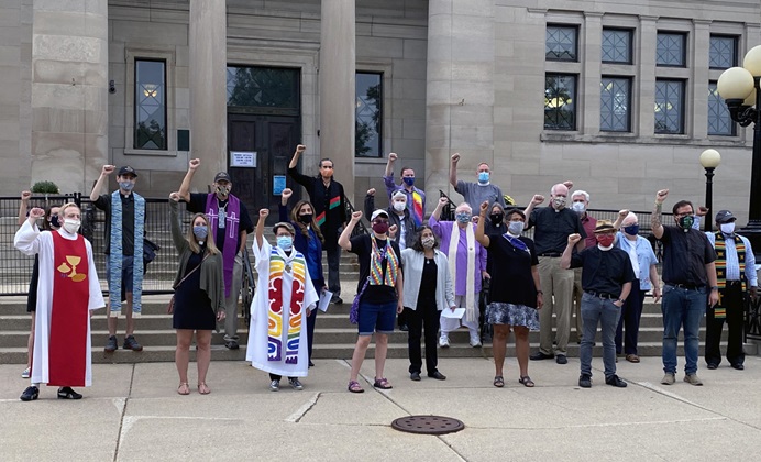 The Rev. Grace Cajiuat (third from left in front row), pastor of Wesley United Methodist Church in Kenosha, Wis., protests with other interfaith religious leaders at Simmons Library Park on Sept. 1, the day President Trump visited the city near Milwaukee. Photo by Chris Herigstad.