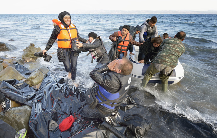 When he landed on the Greek island of Lesbos on Oct. 30, 2015, Nabil Minas, a Christian refugee from Syria, carried his children through the water and left them on the shore, then fell on his face and kissed the ground. The shore where he kneels is covered with the black rubber of deflated refugee boats. Minas and his family came in the boat from Turkey, paying an exorbitant amount to traffickers who provided the transport.  File photo by Paul Jeffrey/Life on Earth Pictures. 