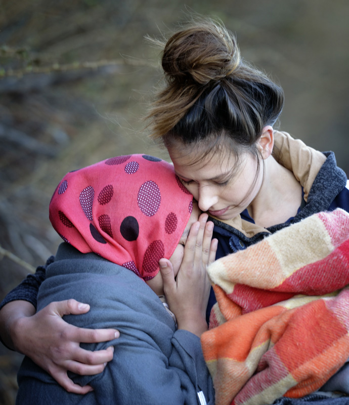 A volunteer embraces a sobbing refugee woman who just landed on a beach near Molyvos, on the Greek island of Lesbos, on Oct. 31, 2015, after crossing the Aegean Sea from Turkey. File photo by Paul Jeffrey/Life on Earth Pictures.