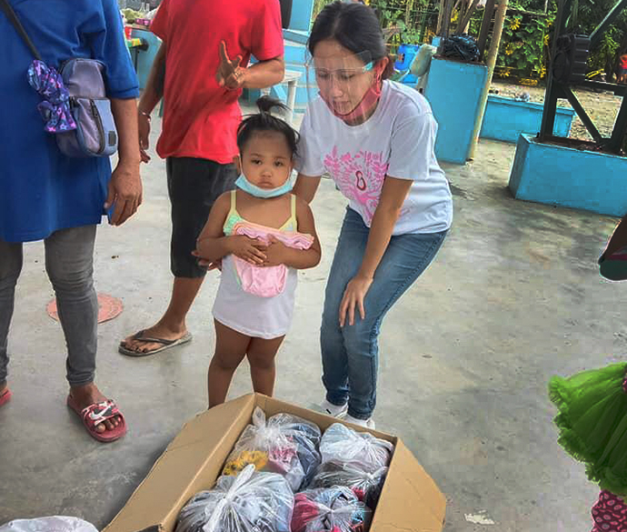 Jazel Resurreccion Lustre, a volunteer teacher in Bulacan province, helps a child from the Longos neighborhood, which was devastated by fire. The September blaze destroyed 28 of 108 homes in the impoverished community. Photo courtesy of Fort Nicolas.