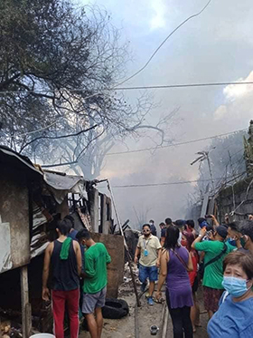 Residents of the Longos barangay, or neighborhood, watch as smoke billows over their neighborhood. A September fire destroyed 28 of 108 homes in the impoverished community in Bulacan province. Photo courtesy of Fort Nicolas.