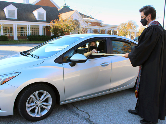 The Rev. Andy Bryan uses an oar to deliver communion elements safely for an Election Day drive-thru communion service at Manchester United Methodist Church in Manchester, Missouri. Photo by Phil Wiseman. 