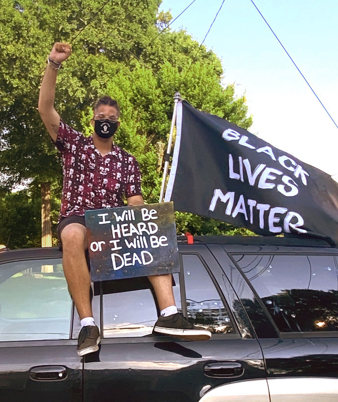 Derian Wilson who protests racism regularly in Macon, Ga., sits atop an SUV during a demonstration. Photo courtesy of Derian Wilson.