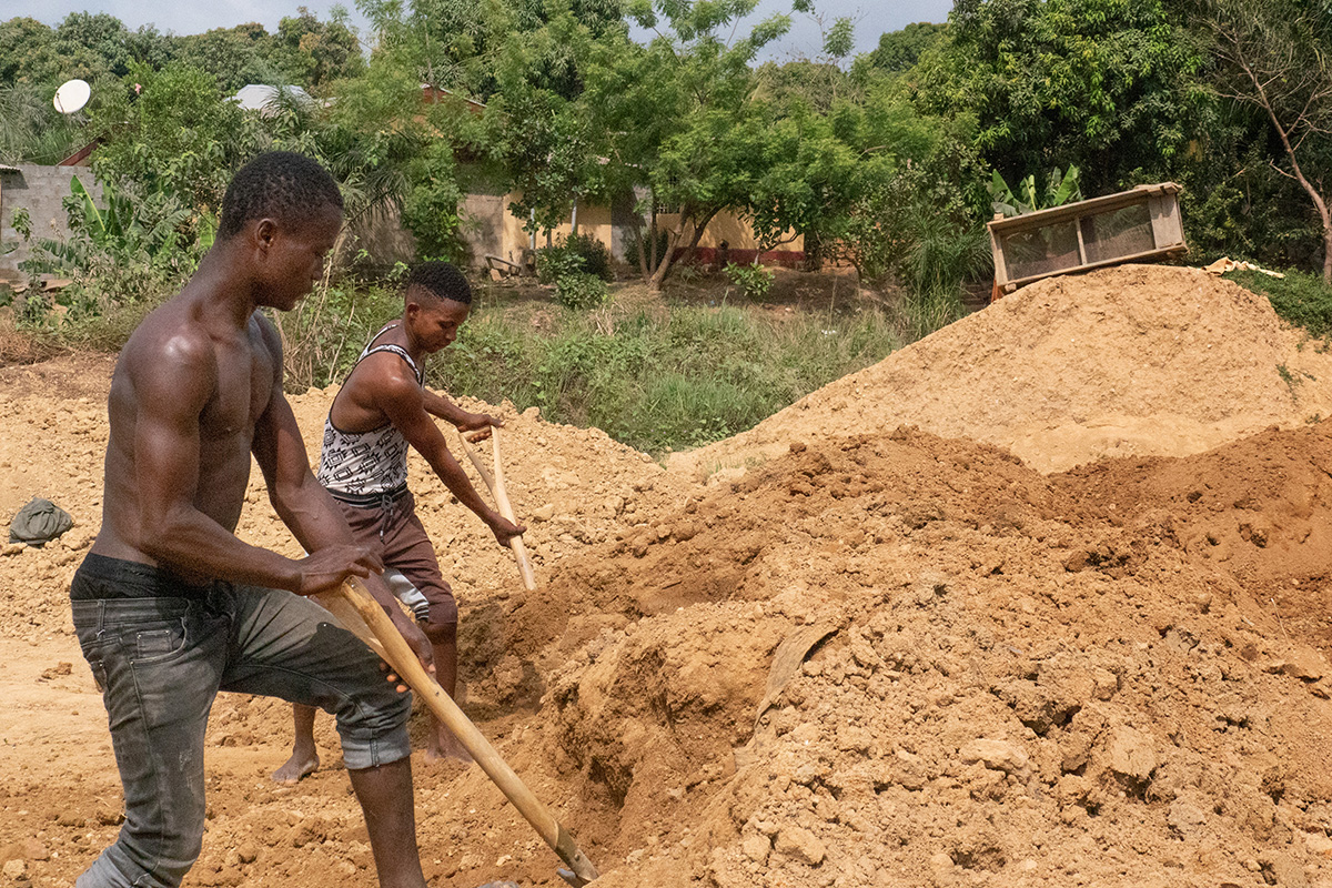 Abdul Conteh (left) and Foday Kamara work for an artisanal diamond miner in Kono, Sierra Leone. Moving large piles of dirt from one location to the next is backbreaking work that pays $2 a day. Artisanal miners are independent and not associated with the large mining companies in the area. Photo by Kathy L. Gilbert, UM News.