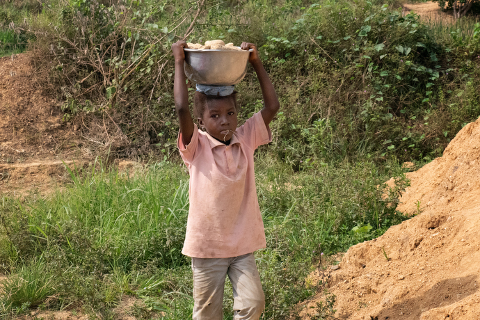 Kaday Kargbo, 5 ans, transporte un chargement de pierres au stand de sa famille situé sur le bord de la route à Kono. La famille brise les plus grosses pierres provenant d’une exploitation minière artisanale de diamants pour les vendre aux personnes qui en ont besoin pour leurs cours ou leurs jardins. Photo de Kathy L. Gilbert, UM News.