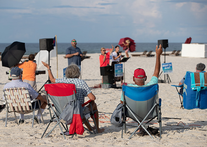 Worshippers raise their arms in praise during the Galilean Beach Service, a ministry of Foley (Ala.) United Methodist Church at Gulf State Park in Gulf Shores, Ala., on Sunday, Aug. 9. The 7:30 a.m. service was over before most other beachgoers arrived. File photo by Mike DuBose, UM News.