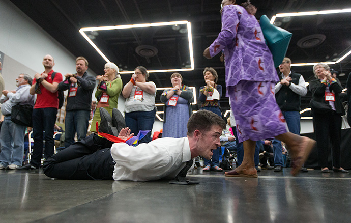 The Rev. Will Green lies on the floor of the 2016 United Methodist General Conference in Portland, Ore., on Tuesday, May 17, 2016. His hands and feet were tied in protest of the denomination's policies on human sexuality. The next meeting of the church’s top legislative body has been postponed to 2021 because of the coronavirus. File photo by Mike DuBose, UM News.