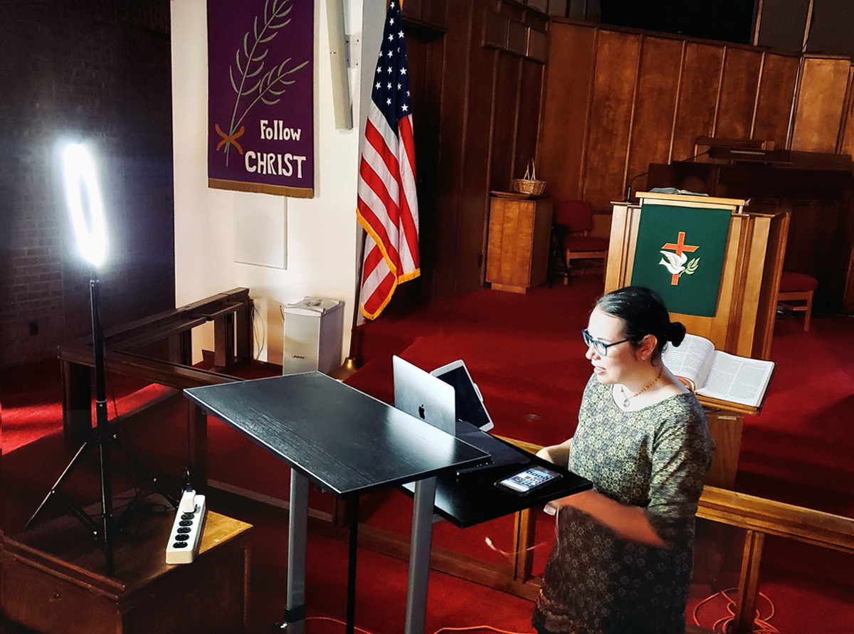 The Rev. Amy Wilson Feltz, pastor of St. Paul’s United Methodist Church in El Paso, Texas, sets up computer equipment to stream a live sermon in the church’s sanctuary in September. Although the pulpit, which is visible on-camera, has the appropriate liturgical color, the banner on the wall was from Lent, when the church had to suspend in-person worship. Photo courtesy of the Rev. Amy Wilson Feltz.