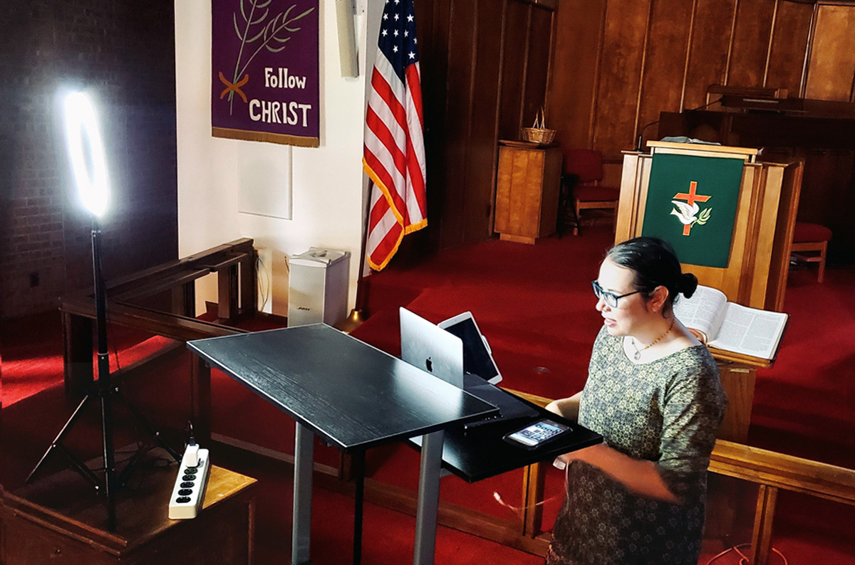 A Revda. Amy Wilson Feltz, pastora da Igreja Metodista Unida de St. Paul em El Paso, Texas, montou um equipamento de computador para transmitir um sermão ao vivo no santuário da igreja em setembro. Embora o púlpito, que pode ser visto pela câmera, tenha a cor litúrgica apropriada, a faixa na parede era da Quaresma, quando a igreja teve que suspender o culto presencial. Foto cedida pela Revda. Amy Wilson Feltz.