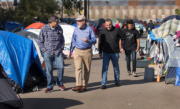 Bishop Felipe Ruiz Aguilar (left) of the Methodist Church of Mexico, the Revs. Jack Amick (center) of the United Methodist Committee on Relief and Edgar Avitia Legarda of the United Methodist Board of Global Ministries survey a makeshift camp for migrants outside the Benito Juarez sports complex in Tijuana, Mexico, in 2018. Global Ministries, the denomination’s largest agency, has been cutting its operating budget significantly over the past few years. File photo by Mike DuBose, UM News.