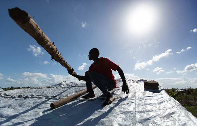 Jorge João Novo lifts a wooden pole into place to help secure an emergency tarp over his home after the roof was peeled off by Cyclone Idai in Búzi, Mozambique, in 2019. The most recent storm, Cyclone Eloise, hit many areas that were just beginning to recover from previous storms. File photo by Mike DuBose, UM News.