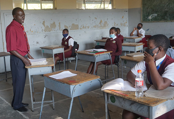 Luckmore Mondiwa enseigne l’histoire à des élèves portant des masques au lycée de Murewa de l’Église Méthodiste Unie, au Zimbabwe. Les élèves et les enseignants du Zimbabwe ont du mal à apprendre et à enseigner puisque les restrictions de confinement liées à la COVID-19 se poursuivent. Photo de Kudzai Chingwe, UM News.