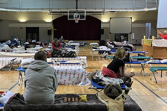 As pessoas que buscam abrigo para escapar da neve e do frio intenso recebem a Sagrada Comunhão no ginásio da Primeira Igreja Metodista Unida em Hot Springs, Ark. A igreja está operando o abrigo de aquecimento em cooperação com a Cruz Vermelha local. Foto de Cindy English.