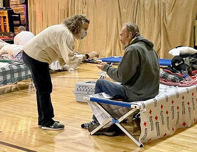 Haley Villines offers Holy Communion to a guest in the church gymnasium serving as a warming shelter at First United Methodist Church in Hot Springs, Ark. Photo by Cindy English.