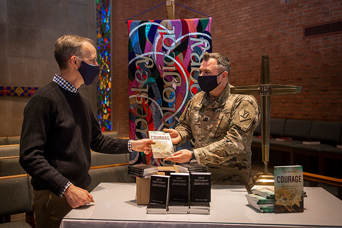 The Rev. Tom Berlin (left) presents a copy of his book, “Courage,” to Massachusetts National Guard Chaplain Chad McCabe in the chapel at Wesley Theological Seminary in Washington. McCabe, whose unit was assigned to help provide security at the U.S. Capitol after the January riot, contacted Wesley Seminary asking for Bibles, novels and board games for troops stationed there. Photo by Lisa Helfert for Wesley Theological Seminary. Copyright 2021. All rights reserved. Used with permission.