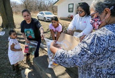 The Rev. Donna Pewo (right),  director of connectional ministries for the Oklahoma Indian Missionary Conference, distributes masks, gloves, hats and blankets to the children at Petarsy United Methodist Church near Lawton, Okla. The National Network of Korean United Methodist Women connected with the OIMC to offer support during the global pandemic by providing clothing items, hand sanitizer, water bottles and 6,000 cloth masks. Photo by Ginny Underwood. The Rev. Donna Pewo (right),  director of connectional ministries for the Oklahoma Indian Missionary Conference, distributes masks, gloves, hats and blankets to the children at Petarsy United Methodist Church near Lawton, Okla. The National Network of Korean United Methodist Women connected with the OIMC to offer support during the global pandemic by providing clothing items, hand sanitizer, water bottles and 6,000 cloth masks. Photo by Ginny Underwood.