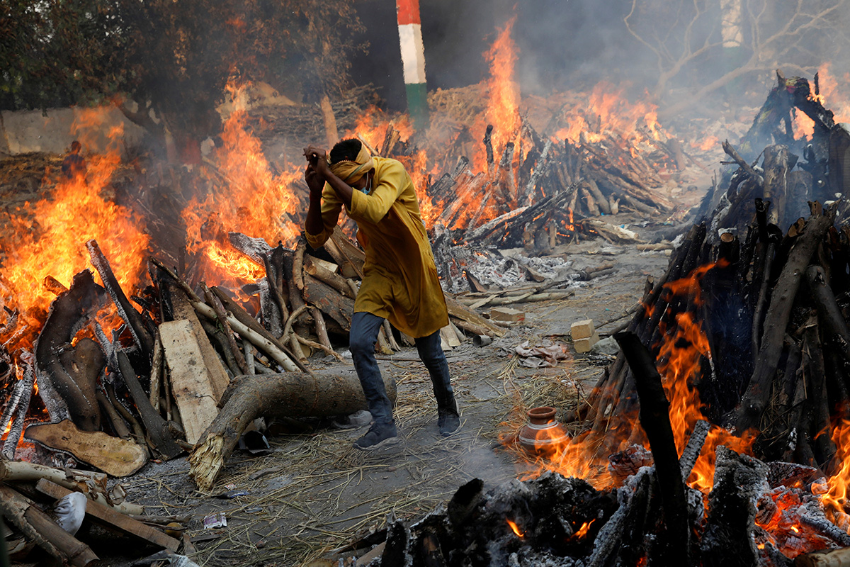 A man runs past the burning funeral pyres of people who died from COVID-19, during a mass cremation at a crematorium in New Delhi, India. The escalating crisis in India will be addressed by The United Methodist Church through grants to entities there who have been partners in the past. Photo by Adnan Abidi, Reuters.