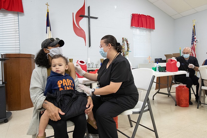 Camisha Henson segura seu filho Welles no colo enquanto recebe a vacinação COVID-19 de Tabitha England, RN, durante uma clínica na Igreja Metodista Unida de St. Mark's em Charlotte, Carolina do Norte.