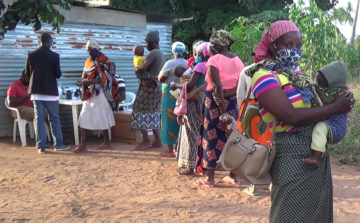 Durante as consultas em Mabumbuza, Moçambique, mães com seus filhos menores passam da esquina farmacêutica para receberem medicamentos. Foto de António Wilson.