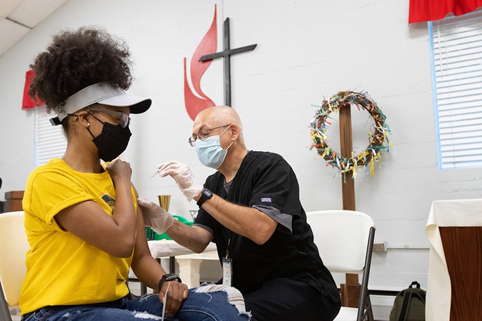 Ashlee Hand recibe una vacuna COVID-19 de EMT Archie Coble durante una clínica en la Iglesia Metodista Unida (IMU) San Marcos en Charlotte, Carolina del Norte, en abril. Los/as expertos/as en salud dicen que muchas personas confían en sus líderes religiosos/as para abordar sus preocupaciones sobre la vacunación COVID-19.