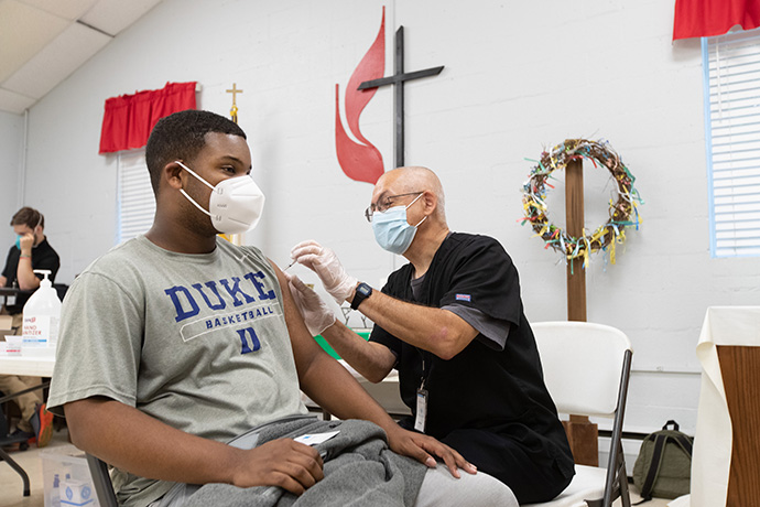 Walter Hand III receives a COVID-19 vaccination from EMT Archie Coble during a clinic at St. Mark’s United Methodist Church in Charlotte, N.C., in April. File photo by Mike DuBose, UM News.
