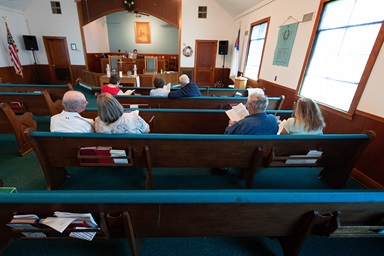 A congregation of seven sings during worship at Oakton United Methodist Church outside Clinton, Ky. Pastor Laura Vincent plays the piano behind the altar. Small, rural churches struggled through the coronavirus pandemic, but many of them are now enjoying the return to in-person services and looking to the future. 