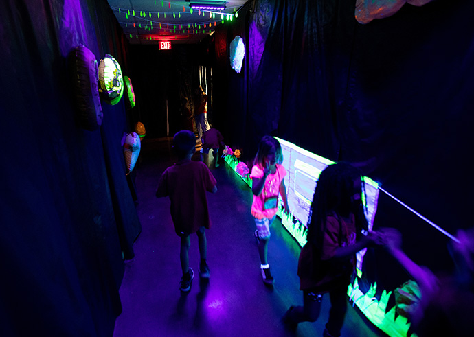 Children make their way through a hallway illuminated with black light during vacation Bible school at Connell Memorial United Methodist Church. The church returned to in-person VBS this year after going virtual in 2020 during the COVID-19 pandemic. Photo by Mike DuBose, UM News.