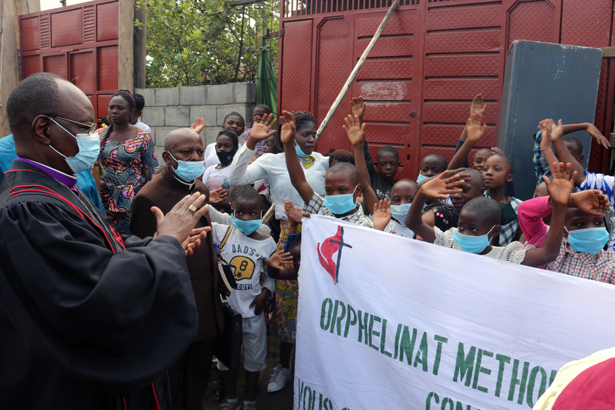 Bishop Gabriel Yemba Unda (far left) is welcomed by orphans at a United Methodist orphanage in Goma, Congo, where he came to assess the difficulties facing children who lost their parents in the May 22 eruption of the Mount Nyiragongo volcano. The United Methodist Church in Congo is helping some 40 orphans who survived the tragedy, which left homes and a United Methodist church buried under lava. Photo by Philippe Kituka Lolonga, UM News. 